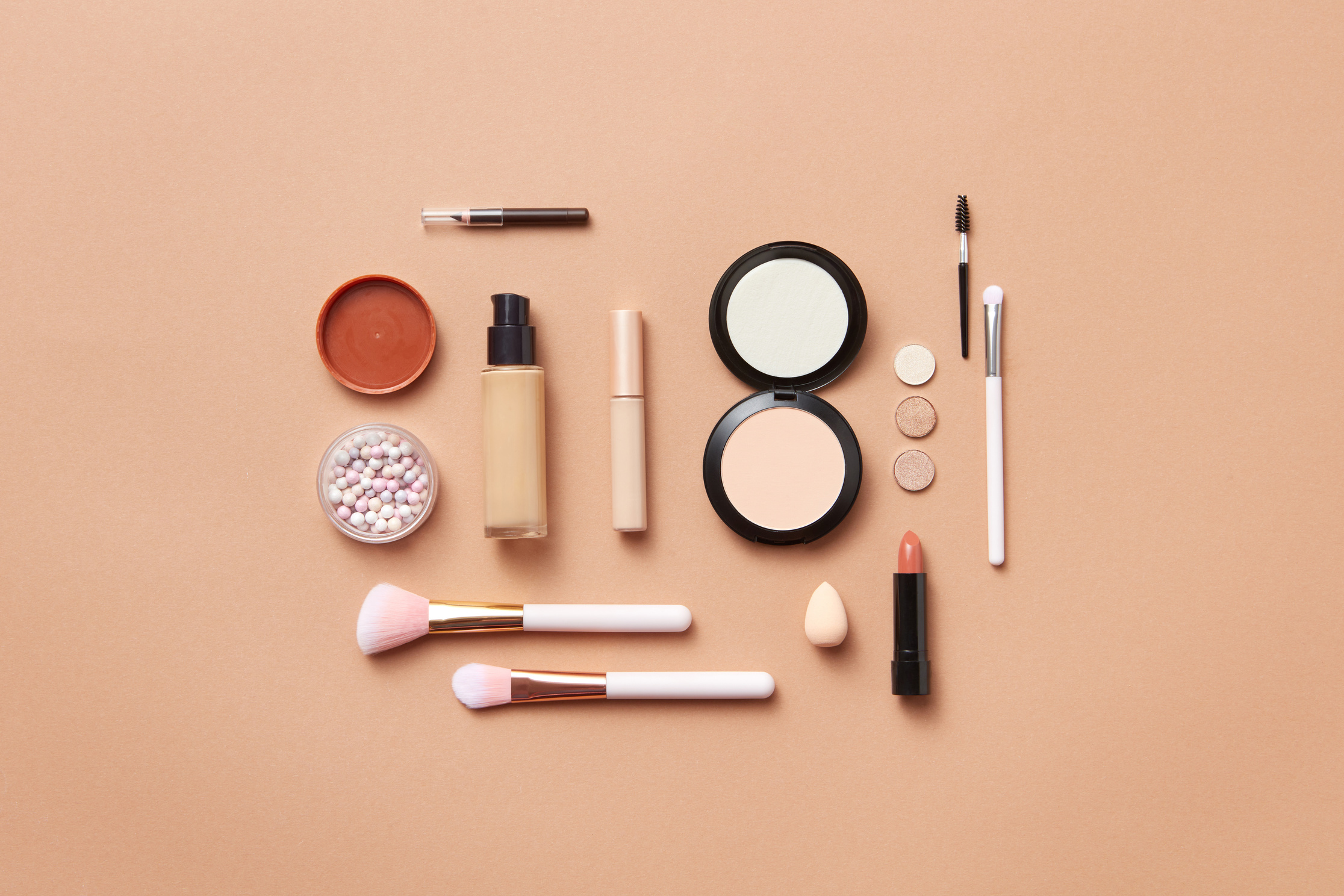 Makeup and Makeup Brushes on Orange Background